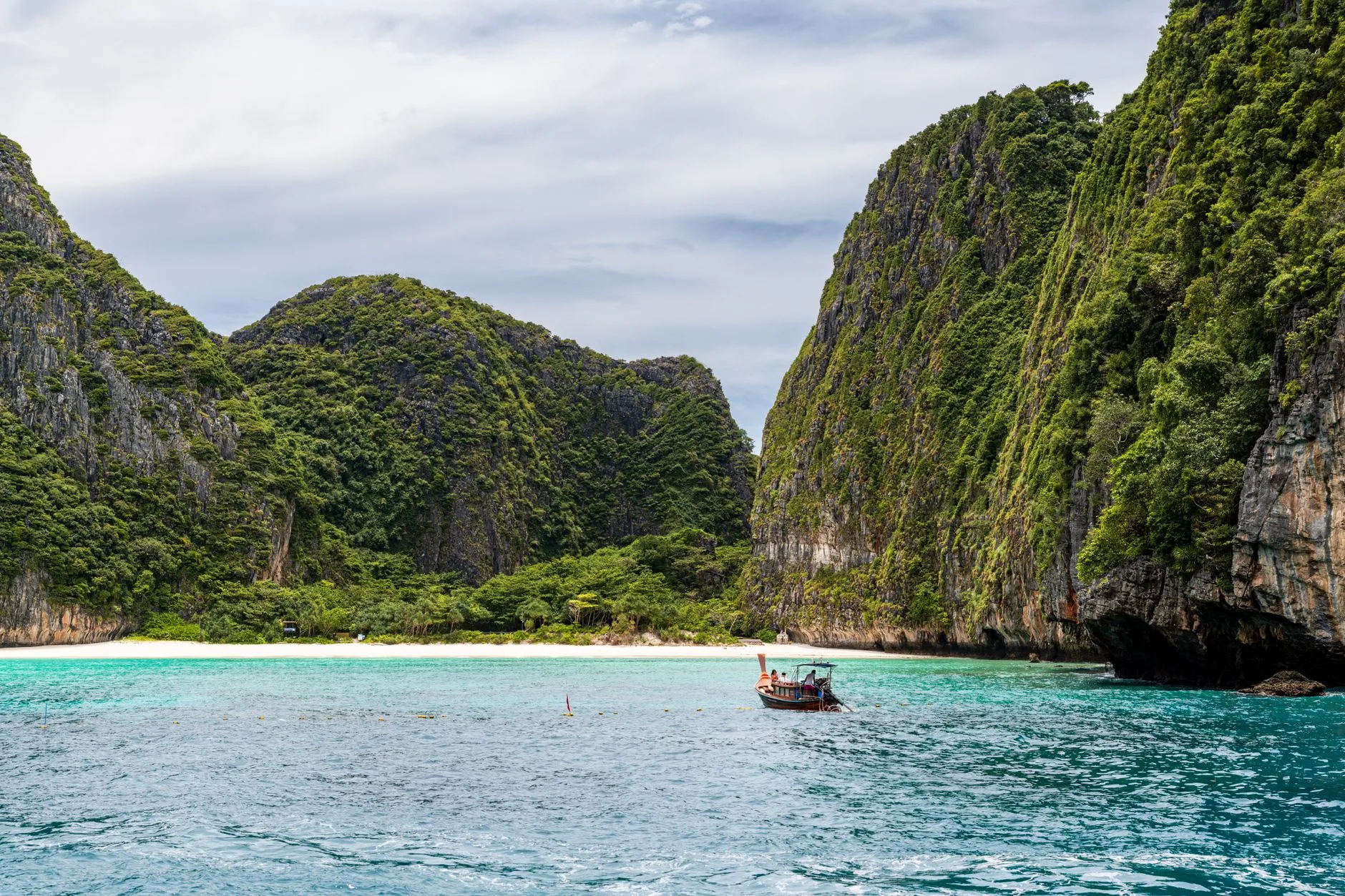 Plage de sable blanc et eaux turquoise en Thaïlande sous un ciel dégagé